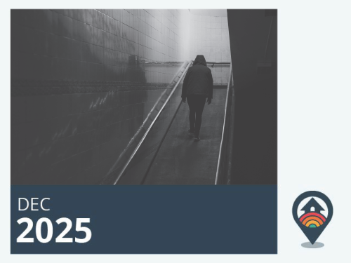 Black and white image of a person walking up a dark stairwell