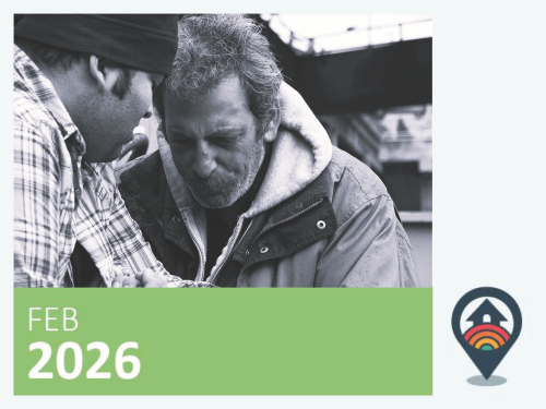 Black and white image of a man looking worn and receiving support from another man